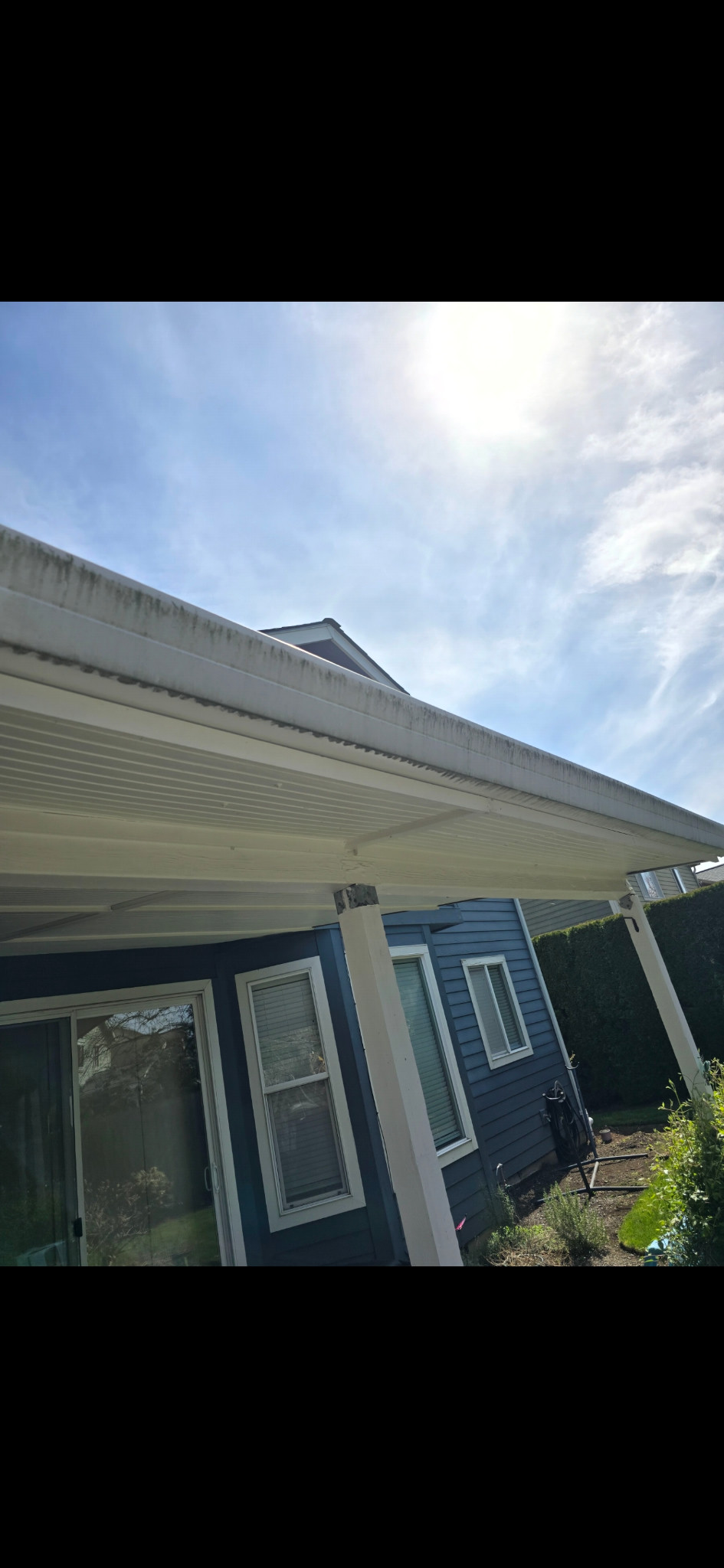 Patio-cover fascia and gutter with dark staining along the visible edge.